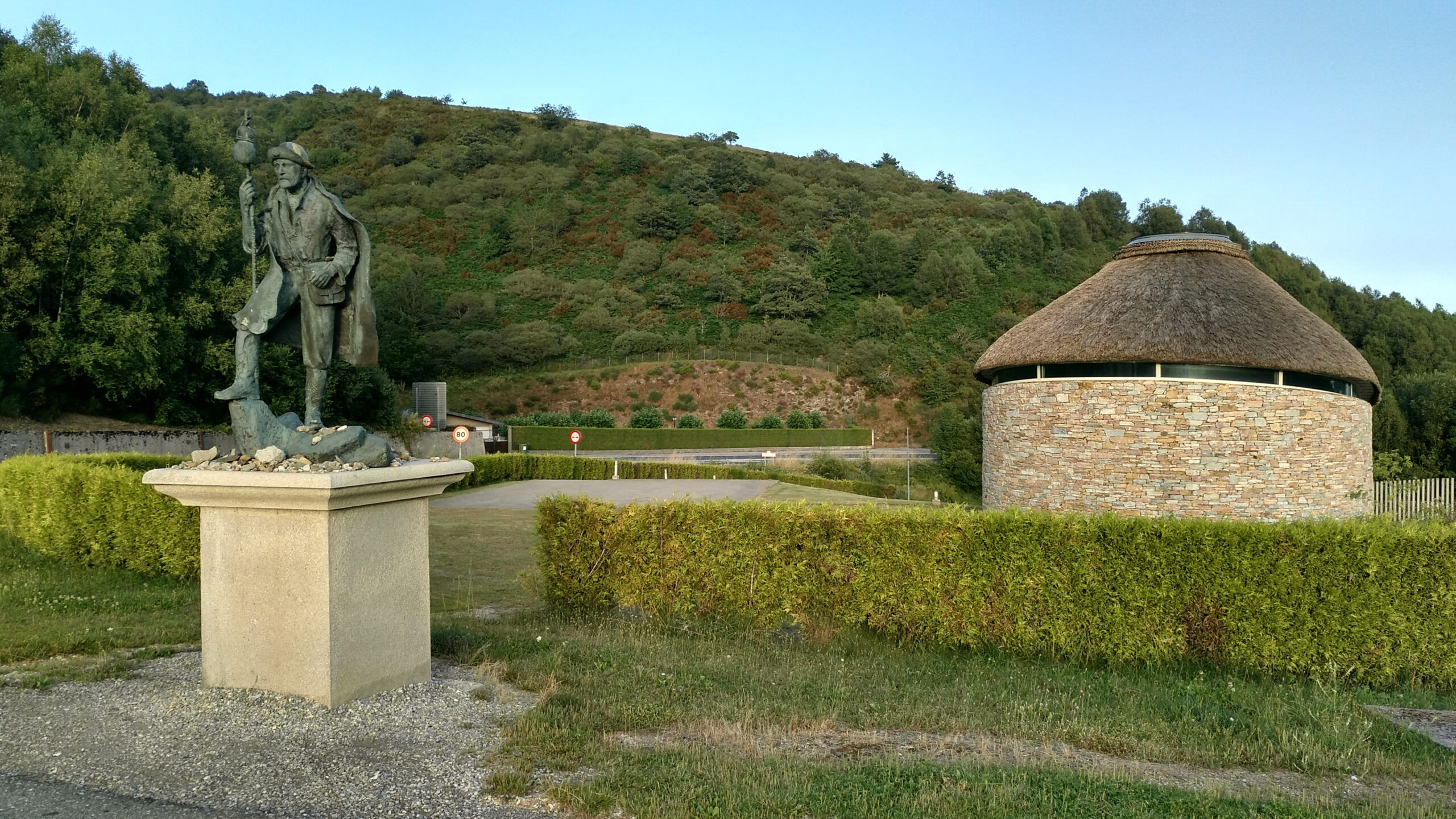 Estatua de Hermann Künig y palloza a la entrada de Pedrafita